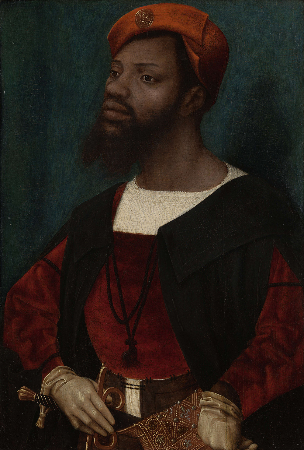 A Black man stands splendidly dressed in European Renaissance garb including a reddish-orange beret, red overgarment, cream-colored gloves, and elaborate jeweled purse. He looks askance from the viewer, right hand positioned on his sheathed sword.